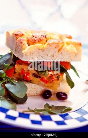 Sandwich of spanish omelette in foccaccia with rocket salad and black olives - Stock Photo