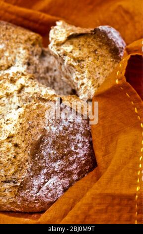 Crusty brown bread in orange napkin - Stock Photo