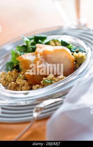 Large flakes of smoked fish with bulgar wheat and salad, on glass plate - Stock Photo