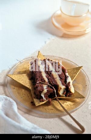 Rich chocolate cake with llayers of butter cream served on star shaped plate with dessert fork - Stock Photo