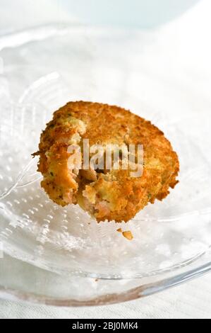 Home made fish cake made with selection of mixed fish and mashed potato on glass plate - Stock Photo