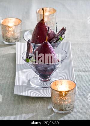 Pears poached in red wine with tealights in party setting - Stock Photo