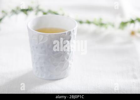 Small porcelain cup of chamomile herb tea - Stock Photo