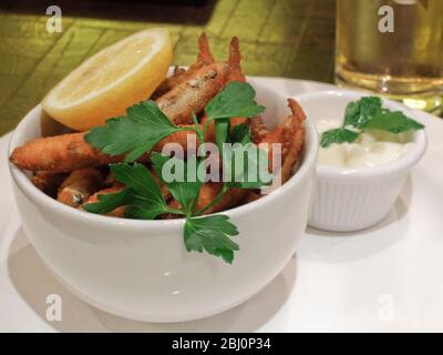 Deep fried whitebait, with lemon wedge and mayonnaise, garnished with flat parsley. - Stock Photo