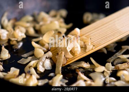Frying chopped onions in black non-stick frying pan - Stock Photo