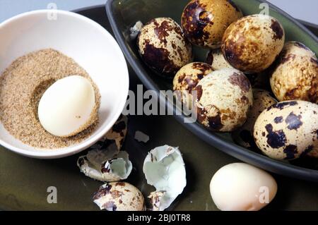 Pottery bowls on blue surface with quails' eggs - Stock Photo