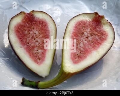Halved ripe fig on white plate - Stock Photo