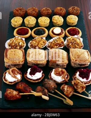 Selection of party foods and savouries on black slate background - Stock Photo