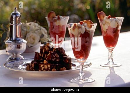 Strawberry champagne sundaes with small chocolate nut brownies as dessert to smart al fresco summer lunch party - Stock Photo