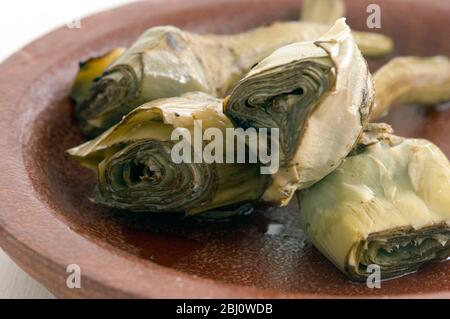 Italian grilled and marinated artichokes on brown dish - Stock Photo