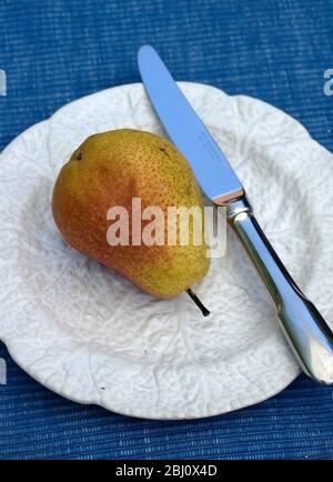 Pear on white cabbage leaf plate with fruit knife - Stock Photo