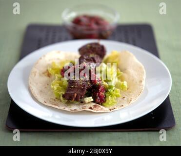 Lamb kebab with salad and fresh tomato sauce on turkish flat bread - Stock Photo