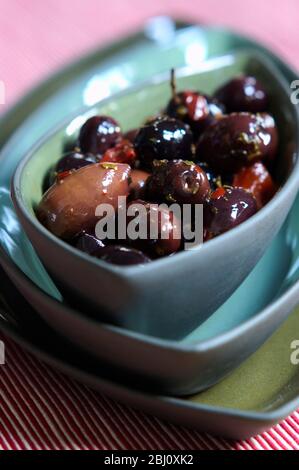 Rustic Italian black olives in bowl on stack of similar green and blue bowls - Stock Photo