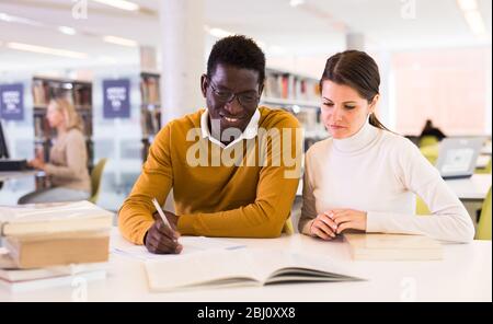 People reading and making notes while preparing for exam in library Stock Photo