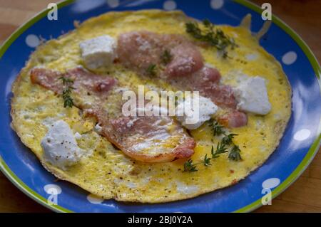 All in one breakfast omelette of eggs with bacon goat's cheese and thyme - Stock Photo