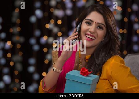woman talking on phone with gift in hand