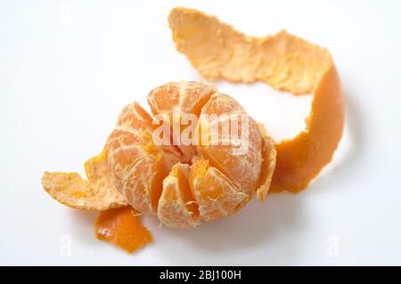 Peeled satsuma on white surface - Stock Photo