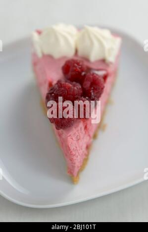 Slice of delicious raspberry mousse cake, on white plate, Short depth of field - Stock Photo