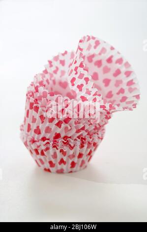 Paper cases for making muffins and fairy cakes - decorated with small red hearts - Stock Photo