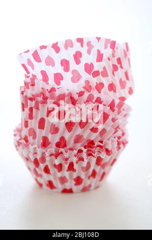 Paper cases for making muffins and fairy cakes - decorated with small red hearts - Stock Photo