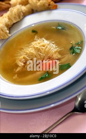 bowl of homemade chicken noodle soup with chunk of crusty bread - Stock Photo
