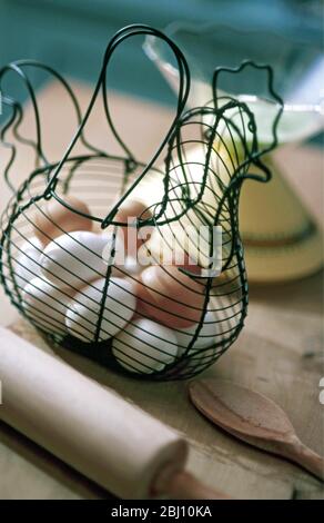 Free range eggs in chicken shaped egg basket with modern weighing scales in background - Stock Photo