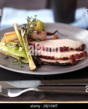 Slices of glazed whole baked ham on plate with vegetables - Stock Photo