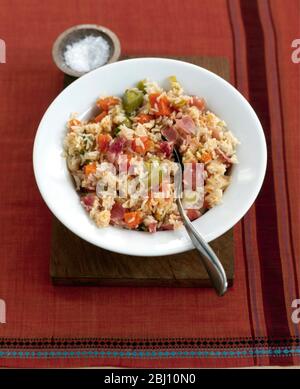 Plate of vegetable risotto on deep white plate on wooden board with small dish of salt - Stock Photo