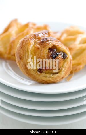 Small danish pastries on stack of white plates - Stock Photo