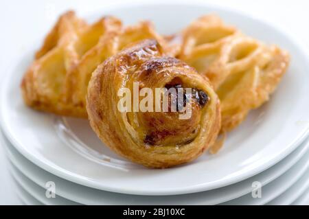 Small danish pastries on stack of white plates - Stock Photo