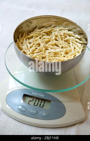 Weighing pasta to control portion sizes - Stock Photo