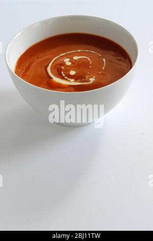 White bowl of tomato soup with swirl of cream - Stock Photo