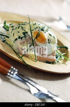 Poached egg on salmon with chopped chives and sauce - Stock Photo