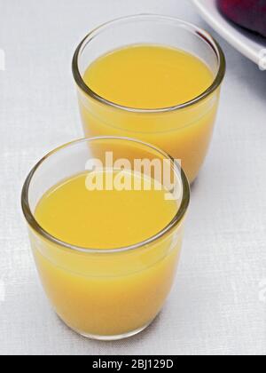 Two glasses of orange juice on white table cloth - Stock Photo