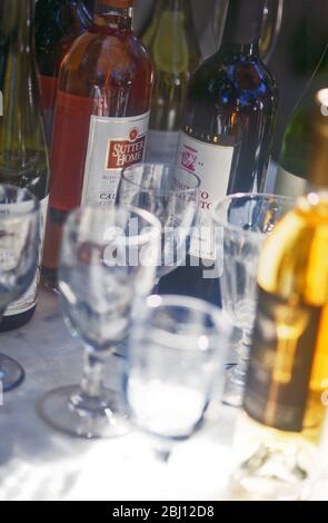 Glasses and wine bottles on table in sunshine and shade - Stock Photo