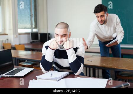 Young guy sitting at classroom worried because of difficulties with studies Stock Photo