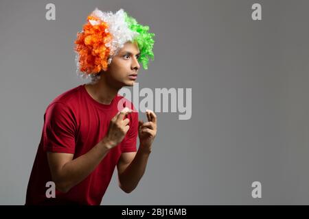 young man wearing tricolour wig wishing for something with fingers crossed, independence day Stock Photo