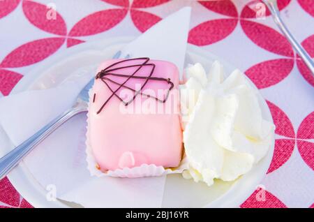 single-twist vanilla and chocolate sponge cakes covered with strawberry icing served with whipped cream Stock Photo