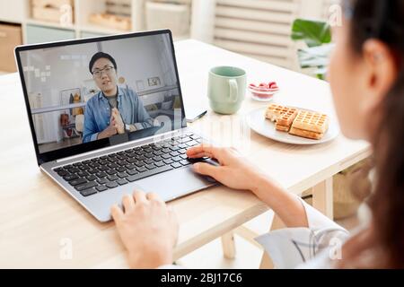 Unrecognizable businesswoman working with Asian man using online technologies on her laptop Stock Photo