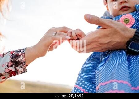 Child's hands on mother and father hands. The concept of summer holiday. Mother's, father's, baby's day. Family spending time together on nature. Fami Stock Photo