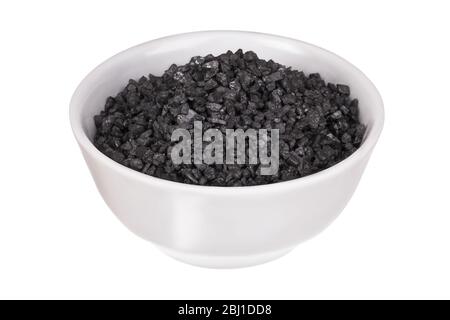 Coarse black salt in a bowl isolated on a white background. Hawaiian lava salt. Himalayan black rock salt. Thursday's salt. Stock Photo
