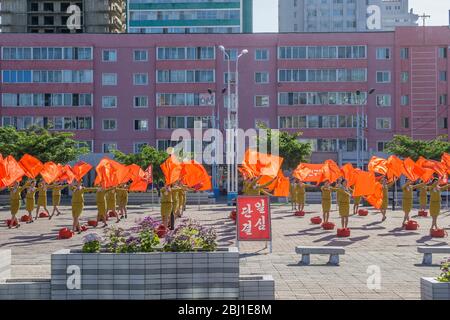 Women wave red flags to encourage people heading to work in Pyongyang, North Korea Stock Photo