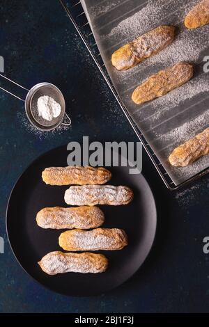 Savoyardi cookies sprinkled with powdered sugar on blue Stock Photo