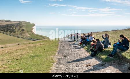 Beachy Head and the English Channel. Teenage students on a lunch break during a school trip to the South Downs on the south coast of England. Stock Photo