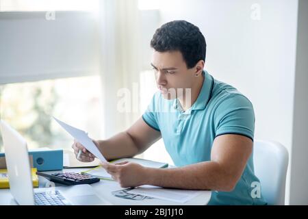 Dark-haired male sitting at his desk, working with papers Stock Photo