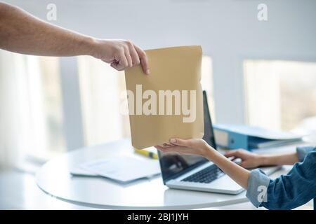 Close-up of female hands taking envelope from male hands Stock Photo