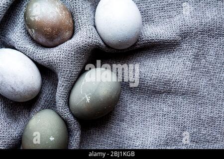 Amazing painted easter eggs. Gray and blue eggs on gray knitted napkin. Cozy Easter at home. Open composition. Natural dye. Copy space. Stock Photo