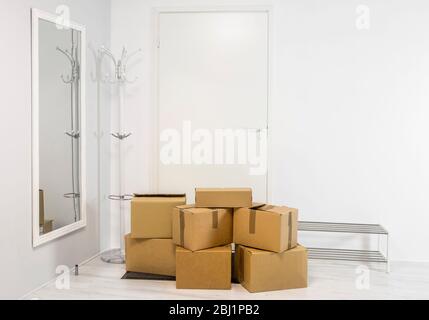 Pile of cardboard boxes in white minimalist white home hallway. Lot of room for text. Stock Photo