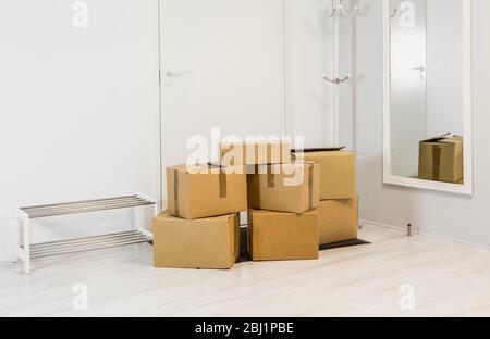 Pile of cardboard boxes in white minimalist white home hallway. Lot of room for text. Stock Photo
