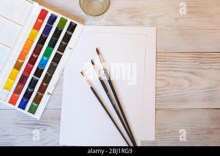 Paint palette with brush and paper on wood table. Top view, flat lay. drawing art creativity, artist concept. Stock Photo